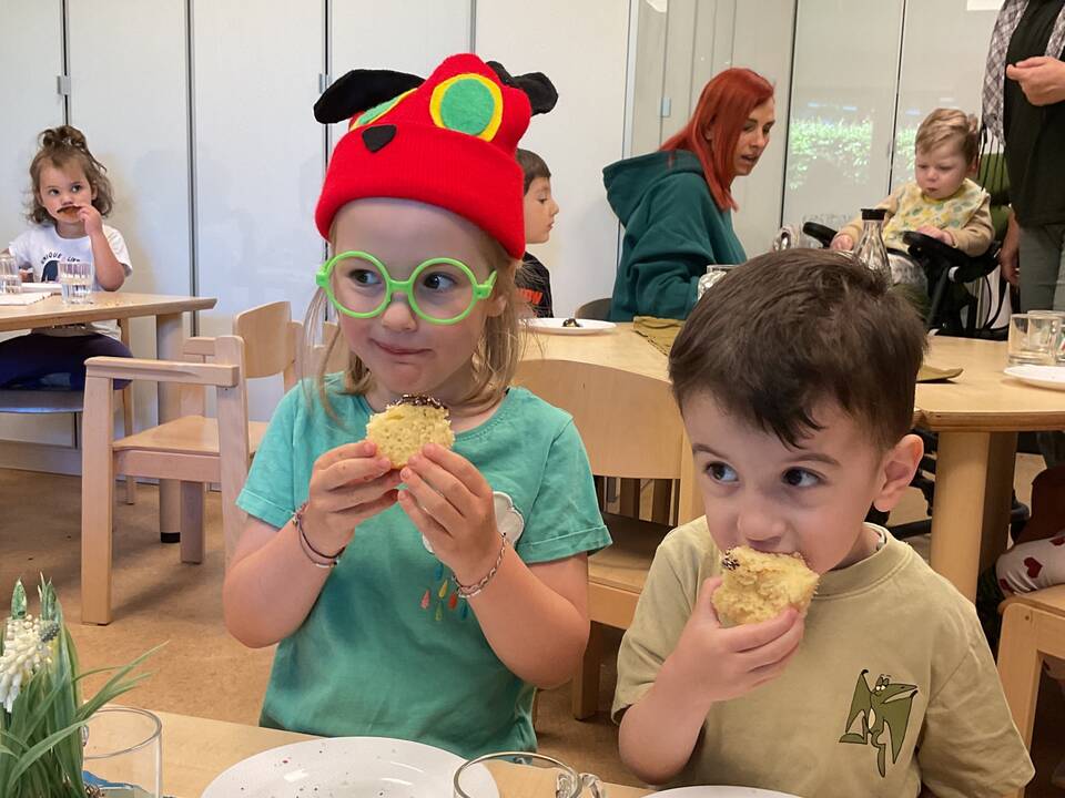Zwei Kinder sitzen nebeneinander und essen Kuchen.