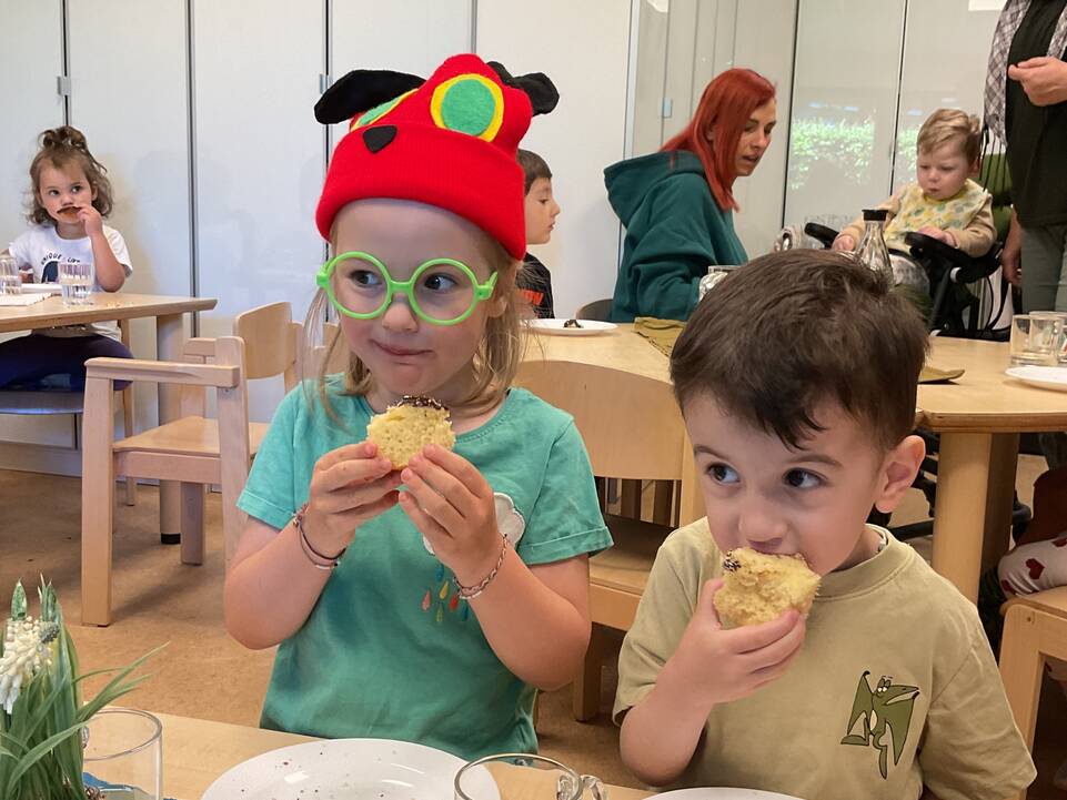 Zwei Kinder sitzen nebeneinander und essen Kuchen.