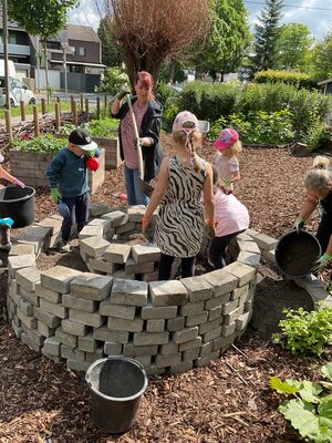 Kinder und Erzieherinnen bauen die Kräuterschnecke.