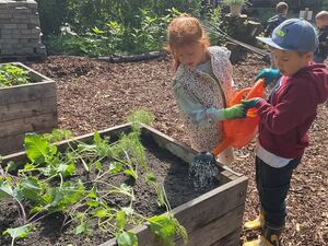 Kinder gießen ein Hochbeet
