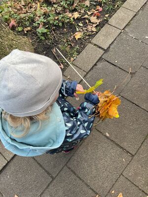 Ein Kind steckt Blätter auf einen Stab.