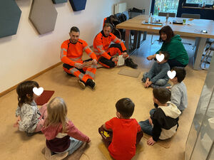 Drei Erwachsene sitzen mit Kindern gemeinsam im Kreis.