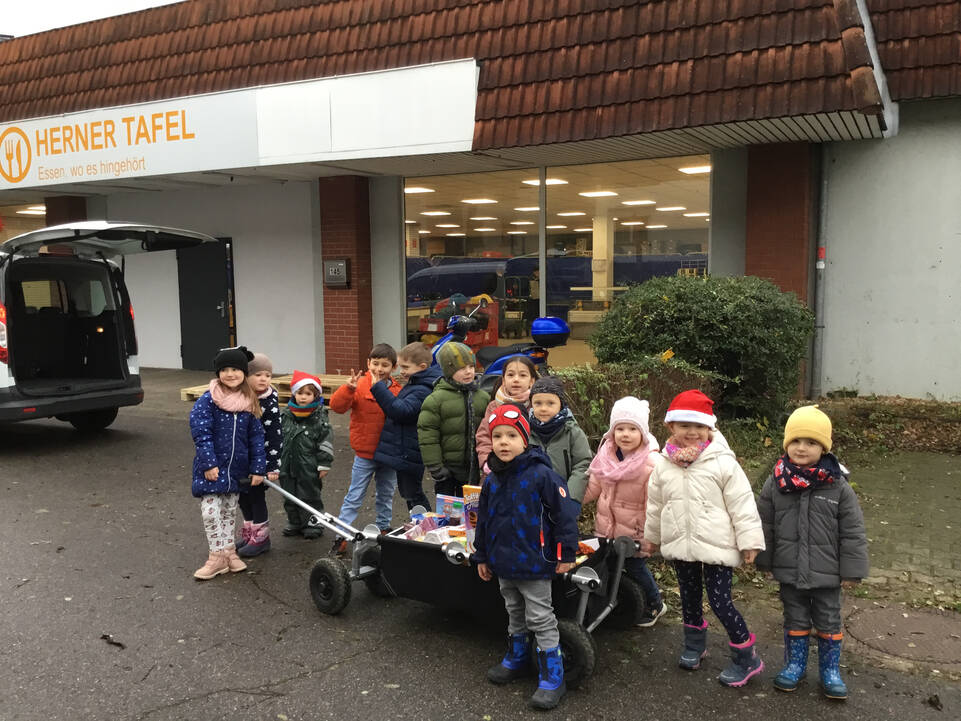 Kinder mit Bollerwagen gefüllt mit Lebensmittel vor Herner Tafel.