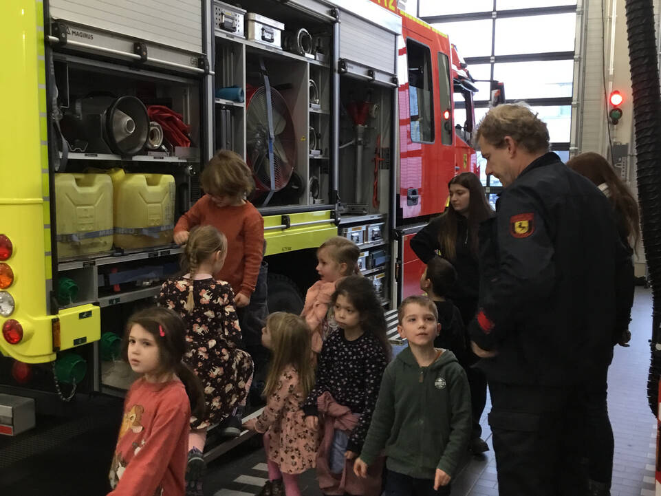 Kinder schauen sich den Feuerwehrwagen genau an.