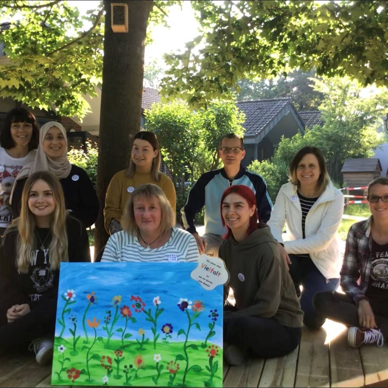 Mehrere Frauen sitzen hinter einem Bild mit einer Blumenwiese