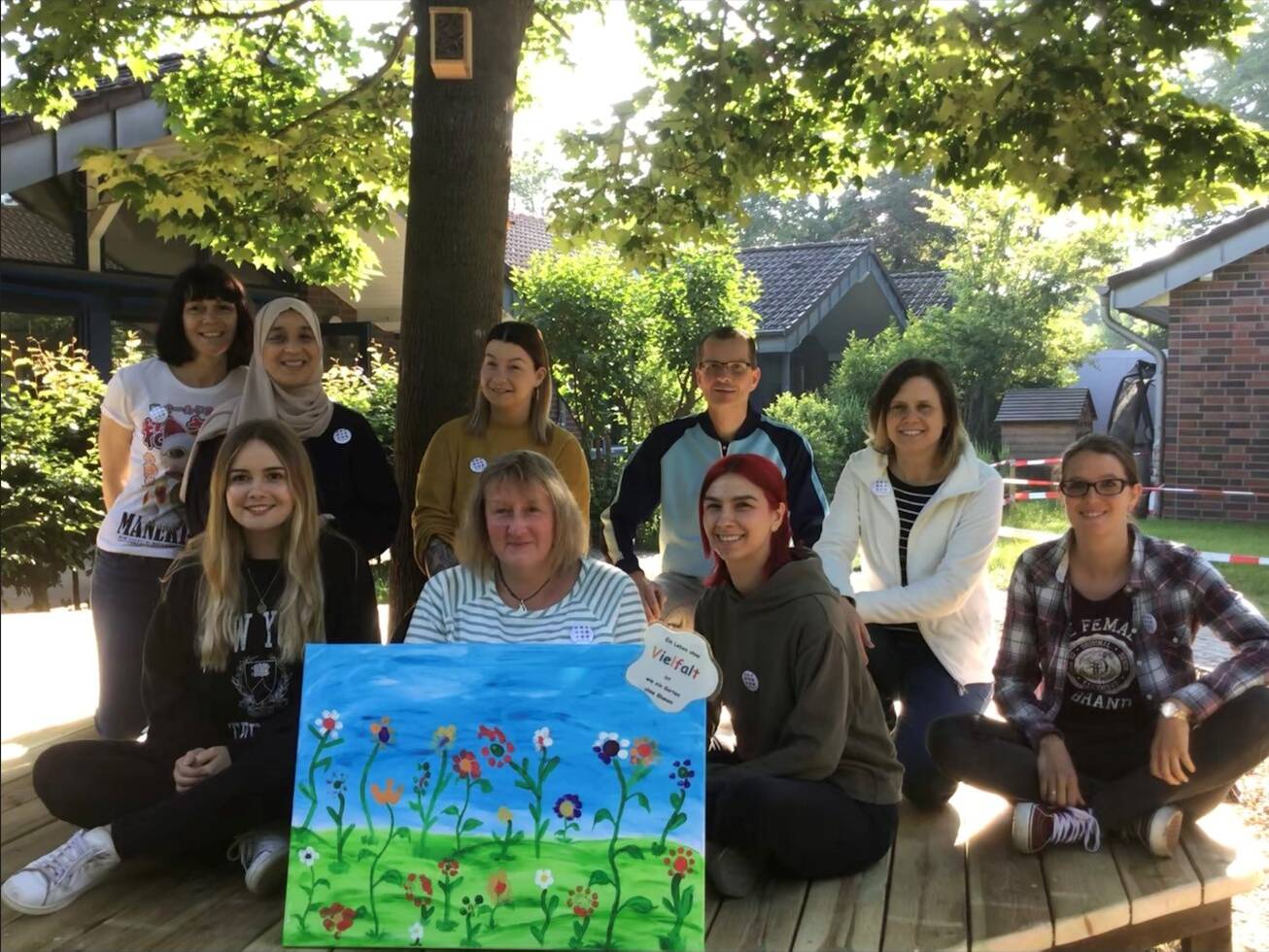 Mehrere Frauen sitzen hinter einem Bild mit einer Blumenwiese