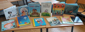 Es sind unterschiedliche Bücher zu sehen, manche sind aufgestellt, manche liegen auf dem Tisch.