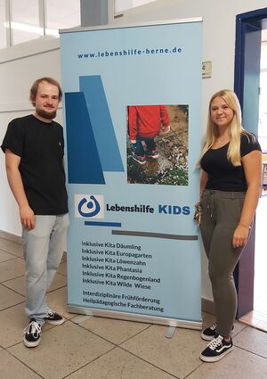 Zwei Personen neben einem Rollup.