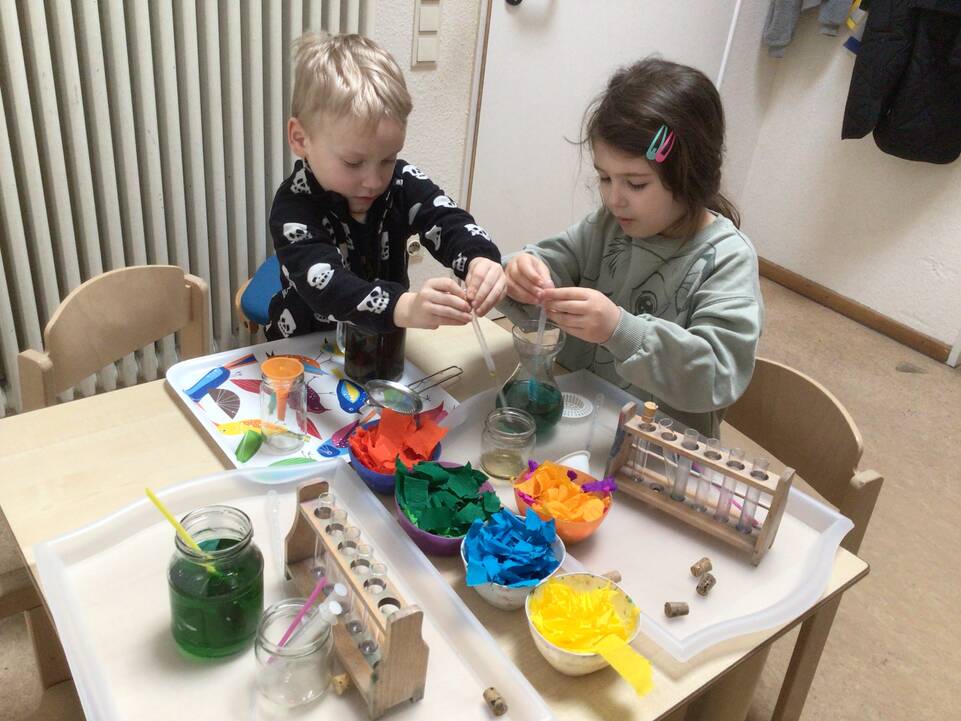 Kinder expirimentieren mit farbigem Wasser.