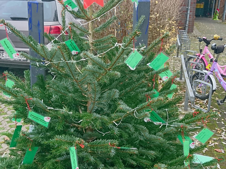 Ein Tannenbazm mit einem roten Stern, einer Lichterkette und vielen grünen Zetteln.