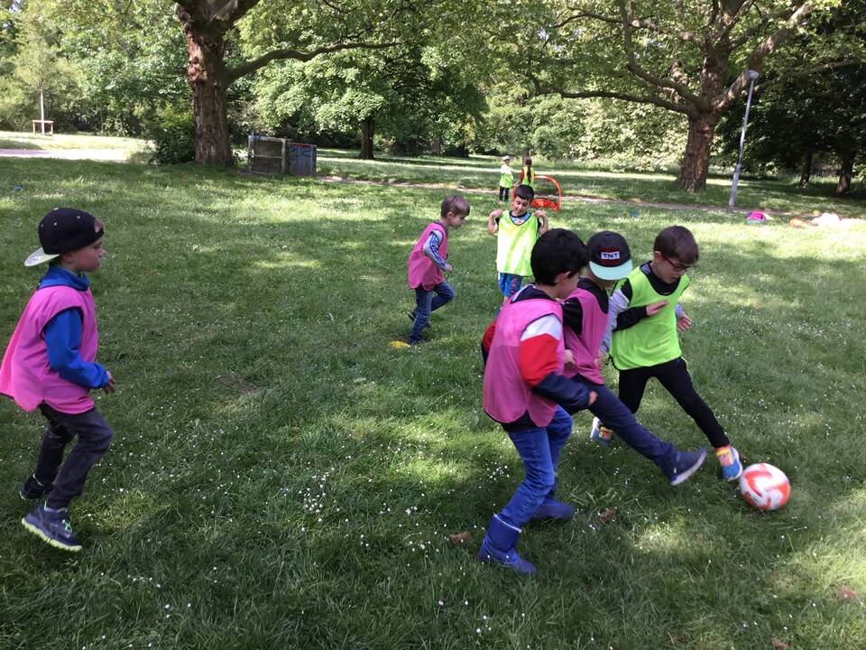 Kinder spielen auf einer Wiese Fussball.