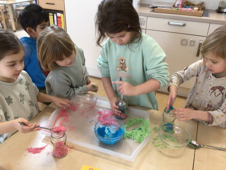 Kinder stehen mit Materialien an einem Tisch.