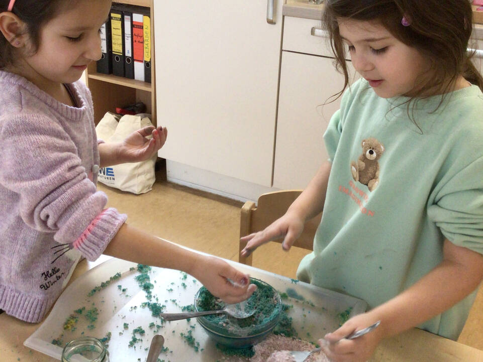 Kinder stehen mit Materialien an einem Tisch.