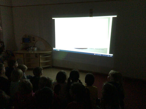 Viele Kinder vor einer erleuchteten Leinwand.