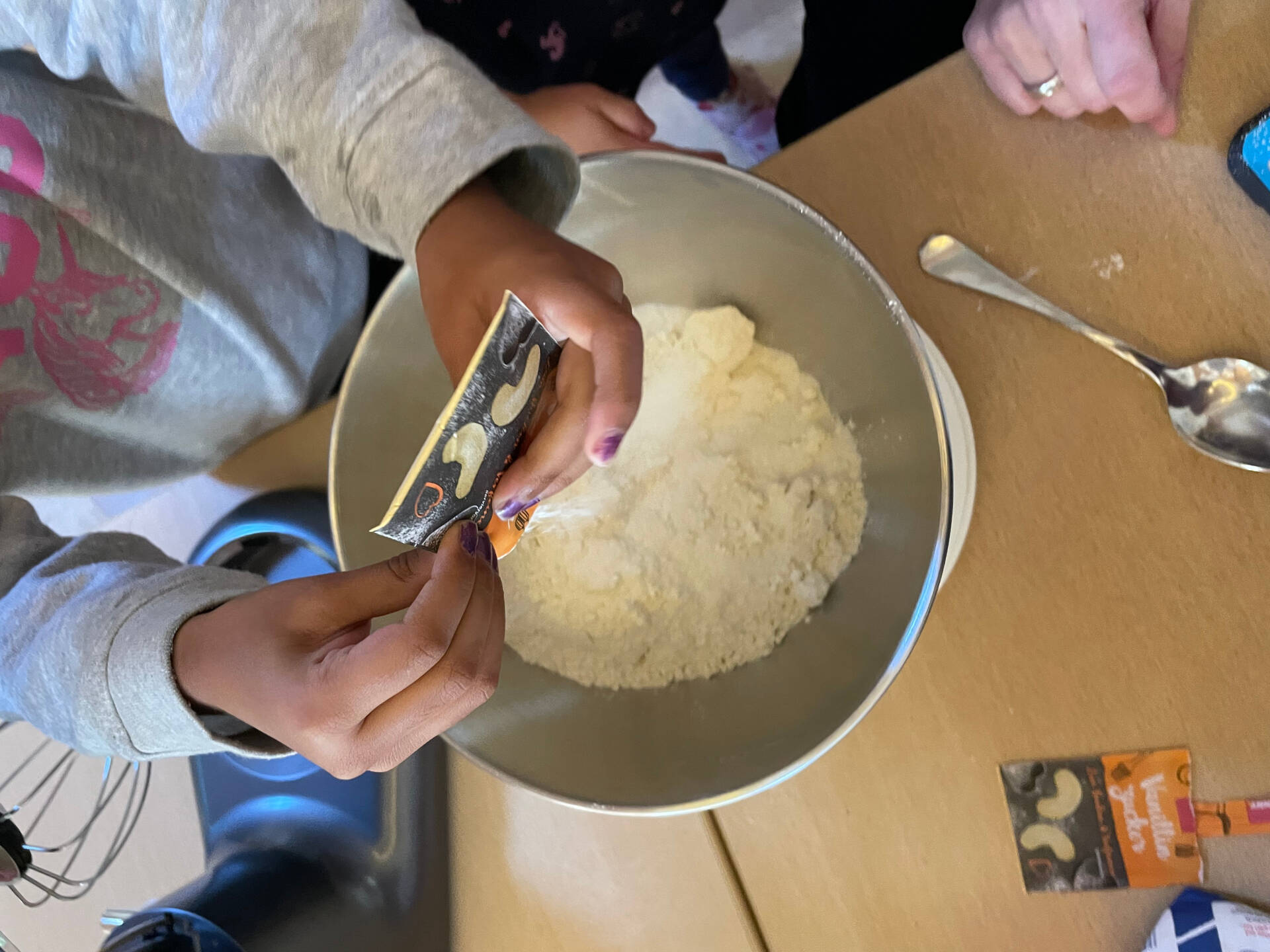 Kinderhände fügen weitere Zutaten in eine Schüssel mit Zutaten.