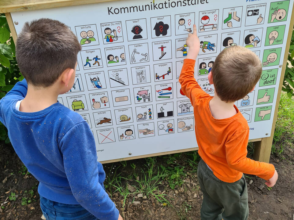 Zwei Kinder vor einer Kommunikationstafel