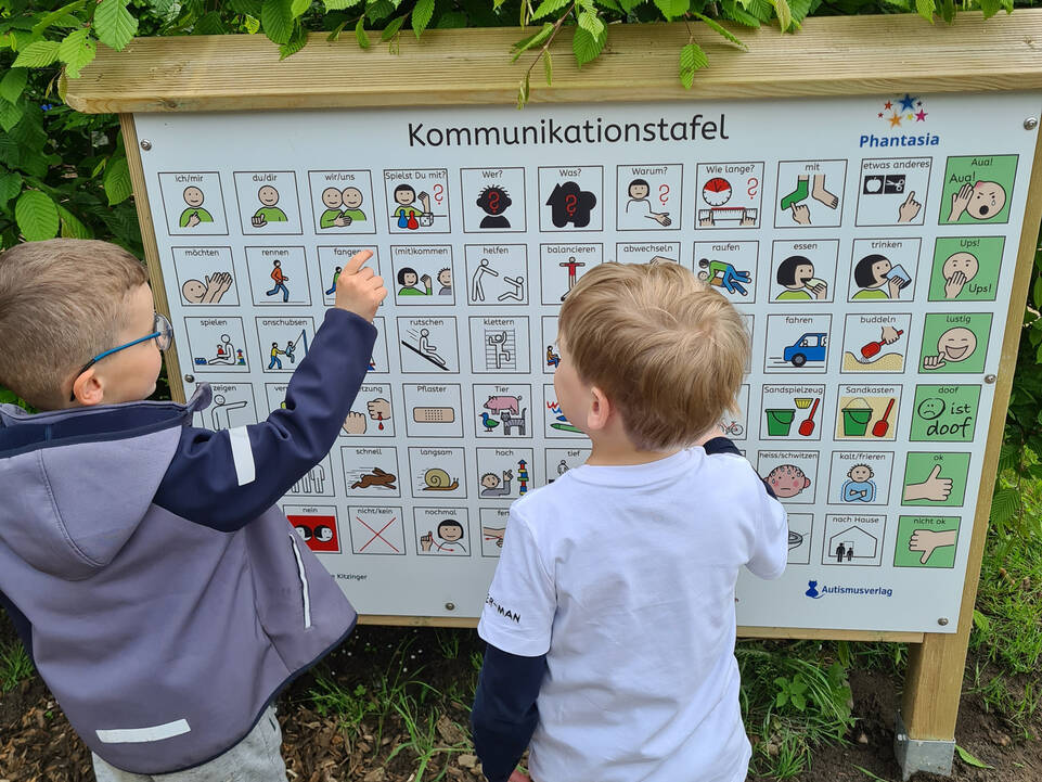 Zwei Kinder zeigen auf eine Kommunikationstafel