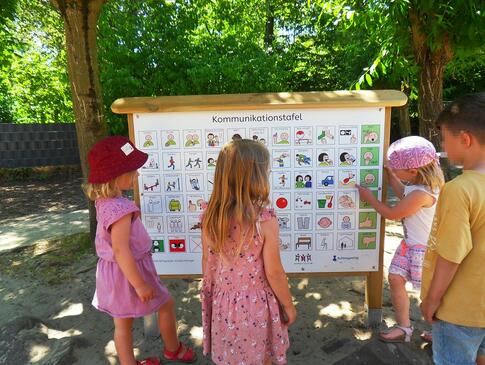 Kinder stehen vor einer Kommunikationstafel