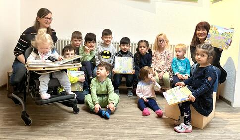 Einige Kinder mit Wimmelbuch in der Hand und eine Erzieherin.