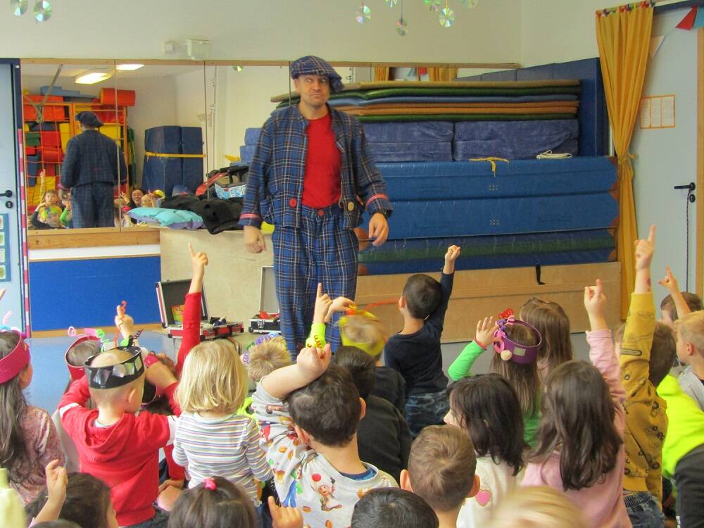 Ein Clown steht vor den Kindern.
