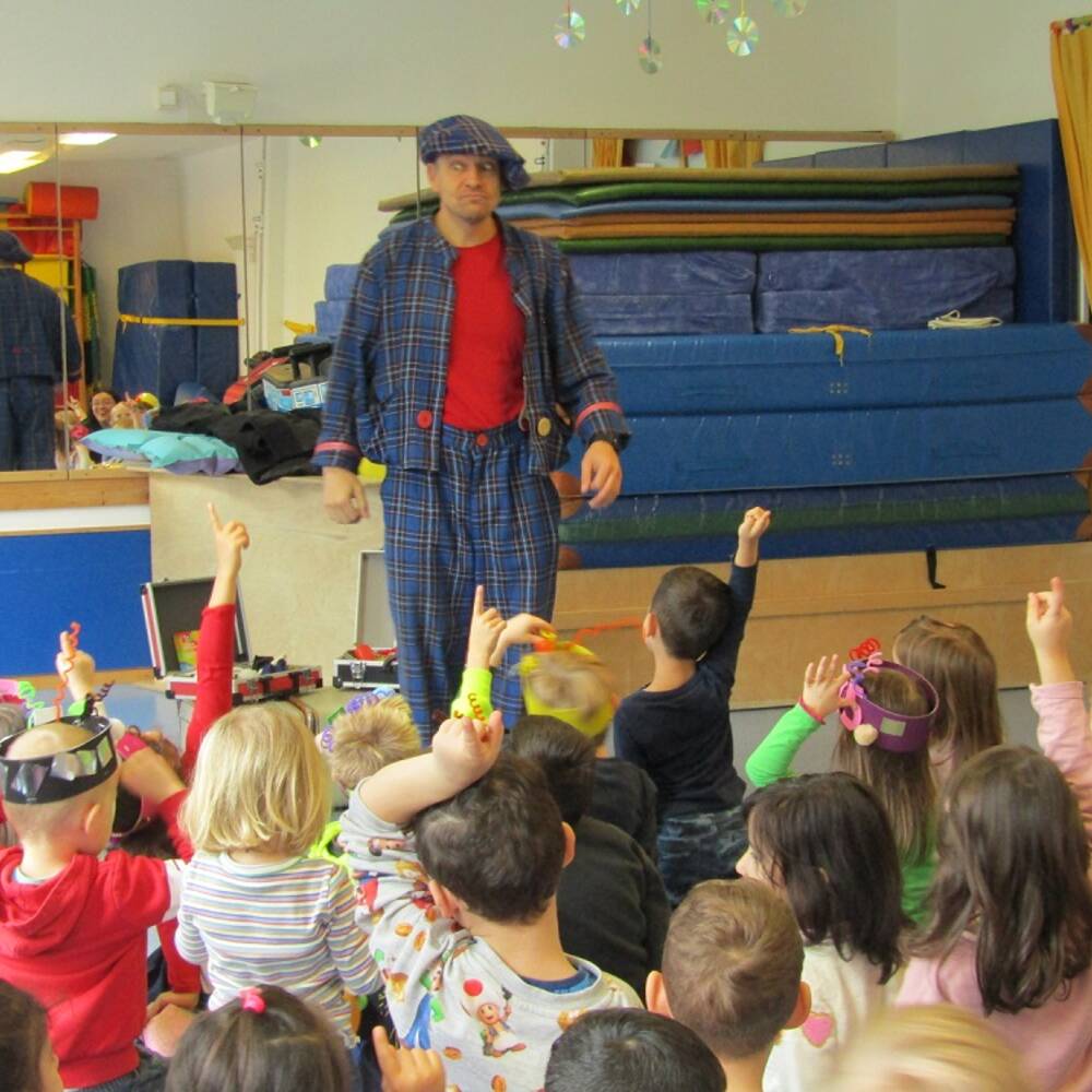 Ein Clown steht vor den Kindern.