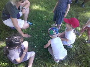 Eine Frau und drei Kinder hocken auf einer Wiese und fühlen.