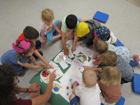 Kinder sitzen in einem Kreis und stimmen an Bildern ab.