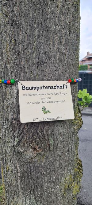 Ein Baum mit Schild wer die Baumpatenschaft übernimmt.