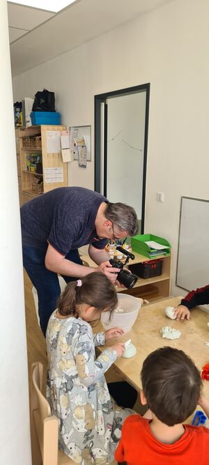 Ein Mann filmt Kindern beim formen von Salzteig.
