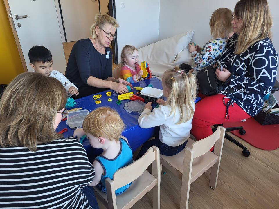 Zwei Frauen sitzen mit Kindern am Tisch und kneten.