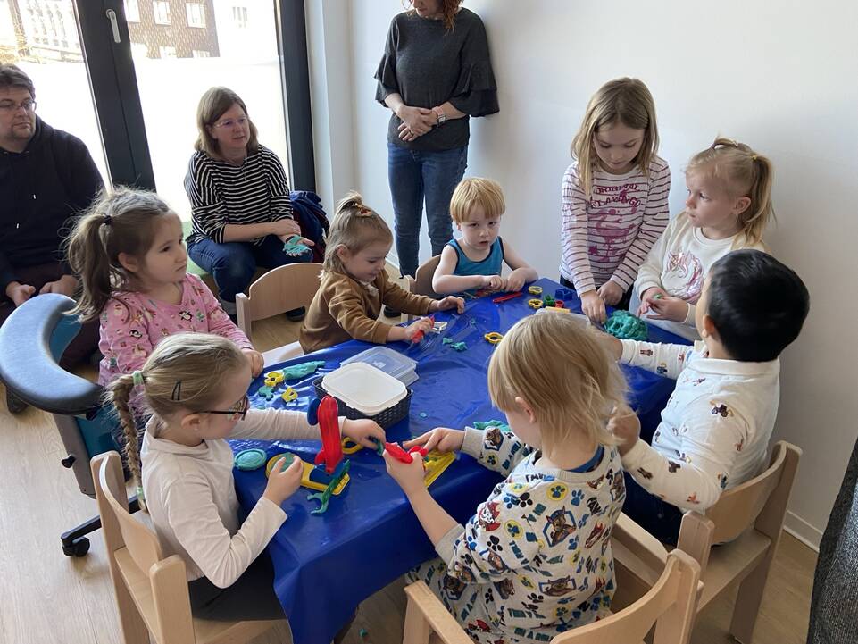 Viele Kinder sitzen an einem Tisch und kneten.