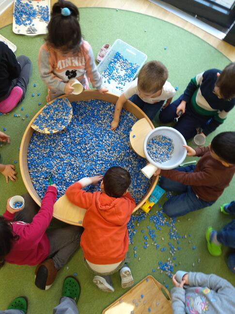 Einige Kinder an einem Becken mit Therapiebohnen.