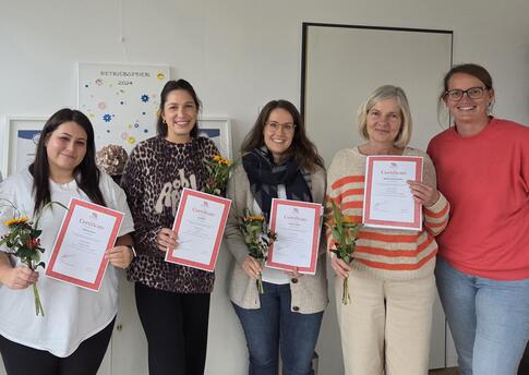 Fünf Frauen, vier mit Rose und einer Urkunde.