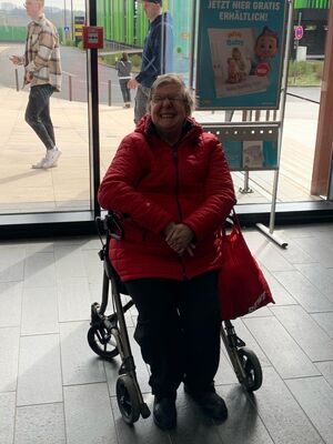 Eine Frau sitzt auf einem Rollator.