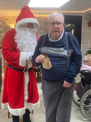 Ein Mann mit einem Geschenk steht neben dem Nikolaus.