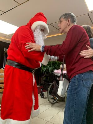 Ein Mann gibt dem Nikolaus die Hand und wird dabei unterstützt.