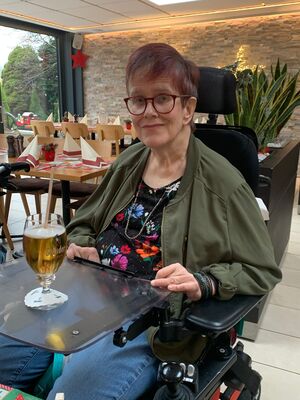 Eine Frau im Rolstuhl mit einem Bier.