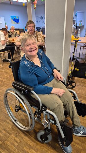 Eine Frau im Rollstuhl lächelt.
