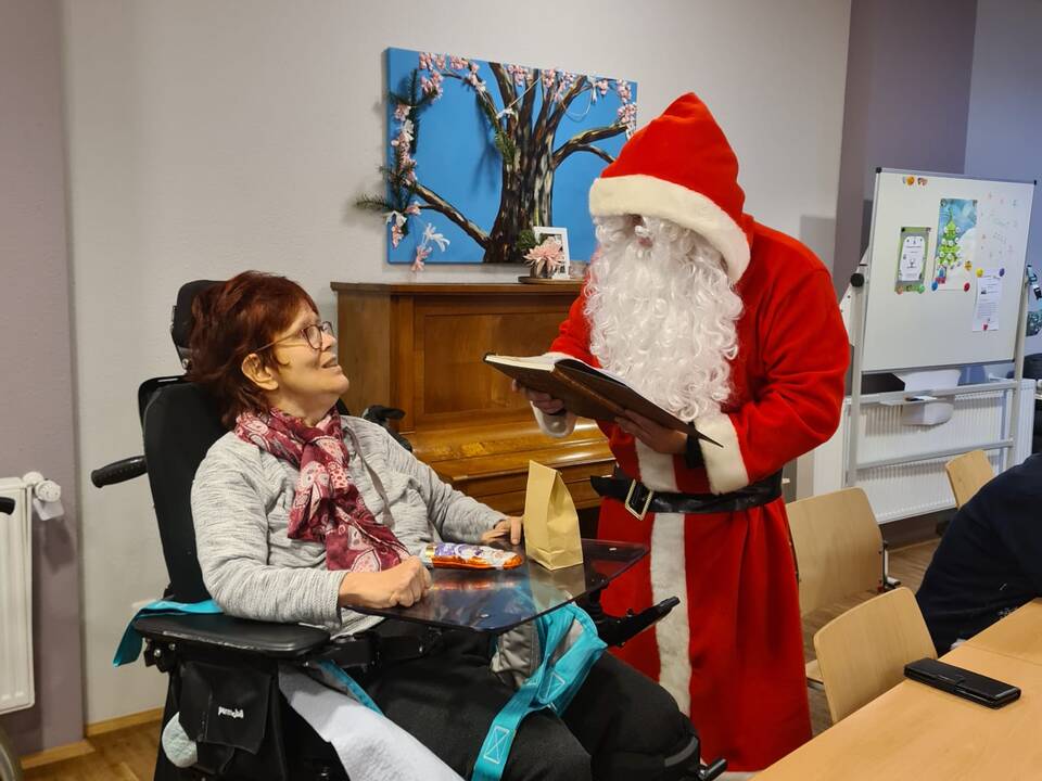 Der Nikolaus sitzt neben einer Frau im Rollstuhl.