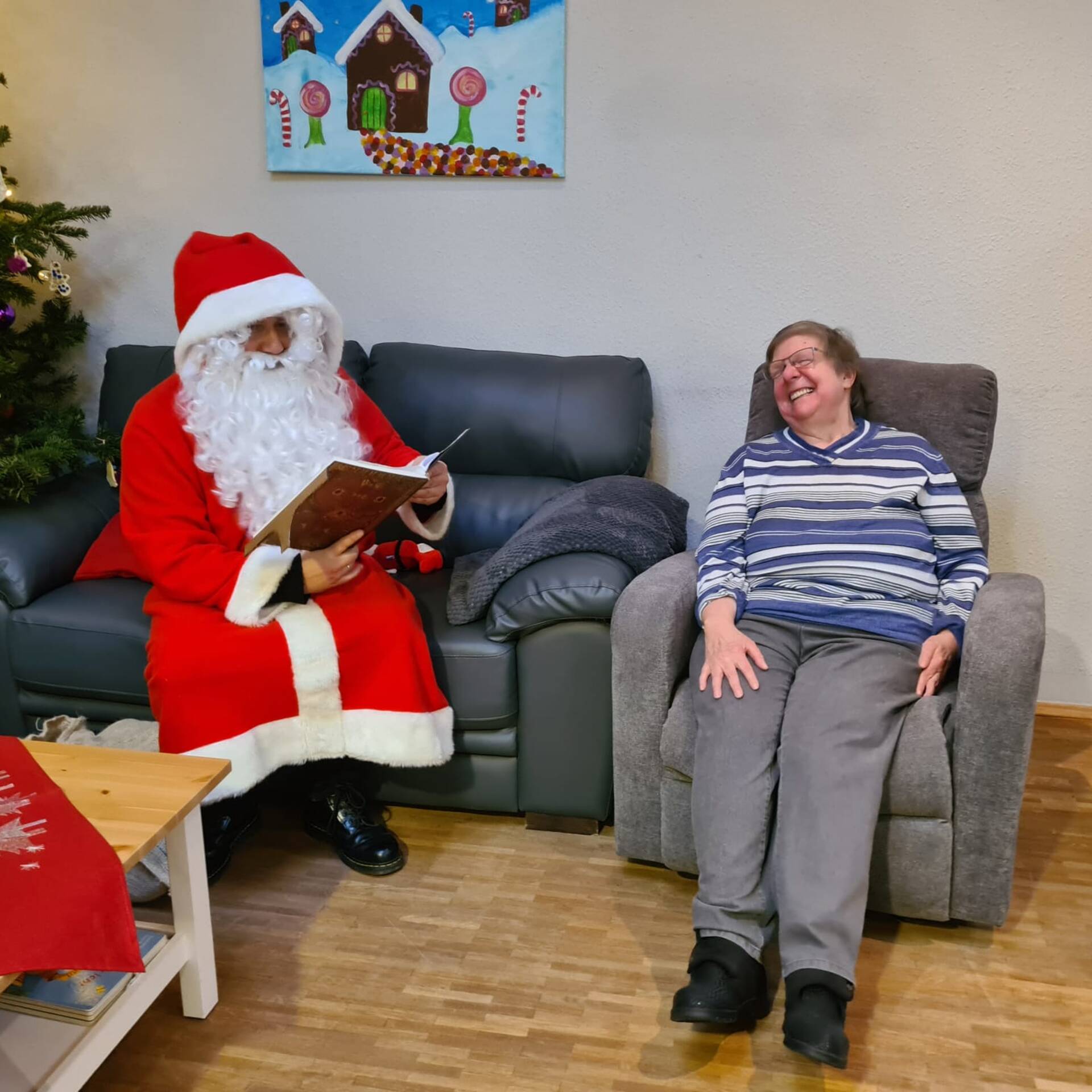 Eine Dame sitzt neben dem Nikolaus im Sessel.