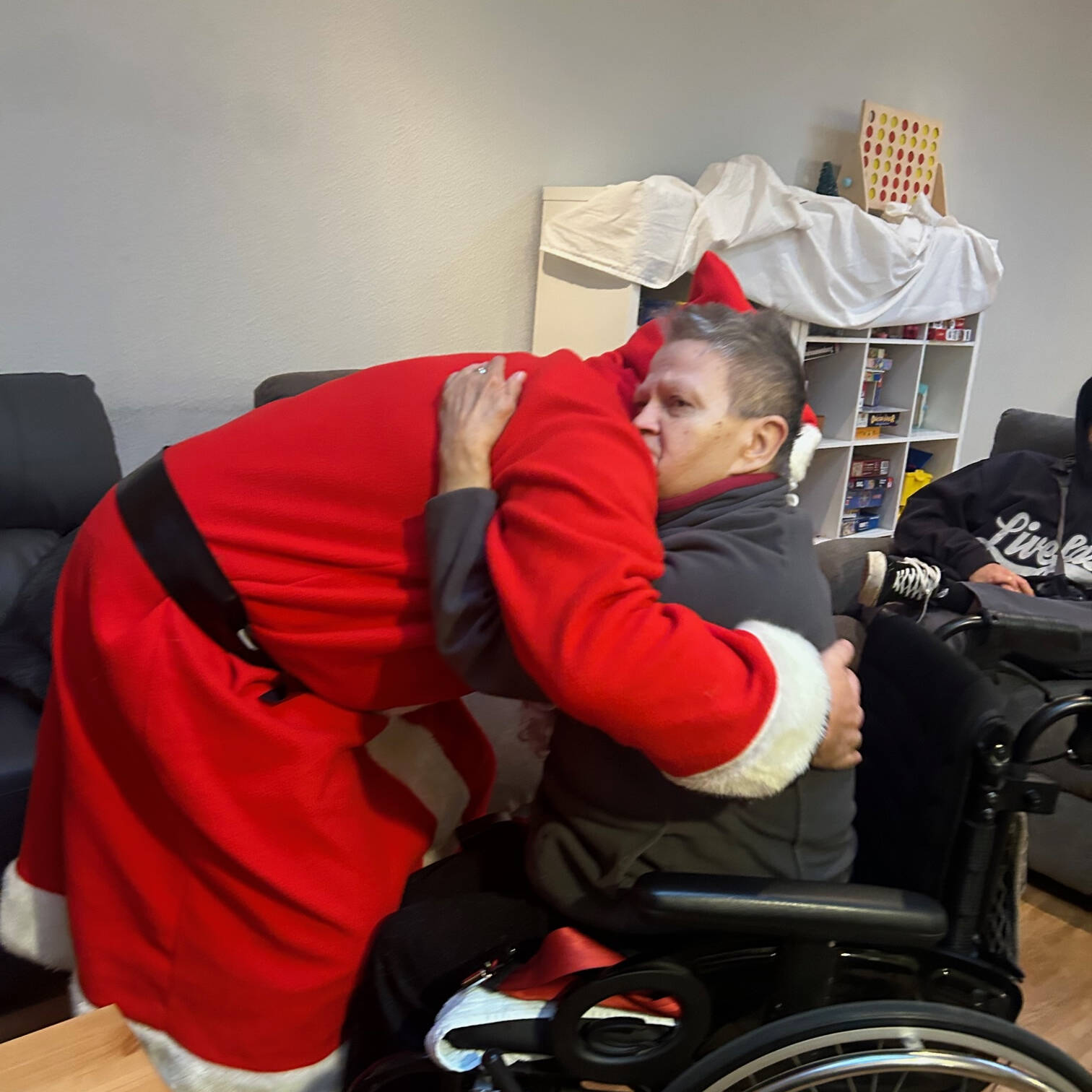Der Nikolaus umarmt eine Person im Rollstuhl.