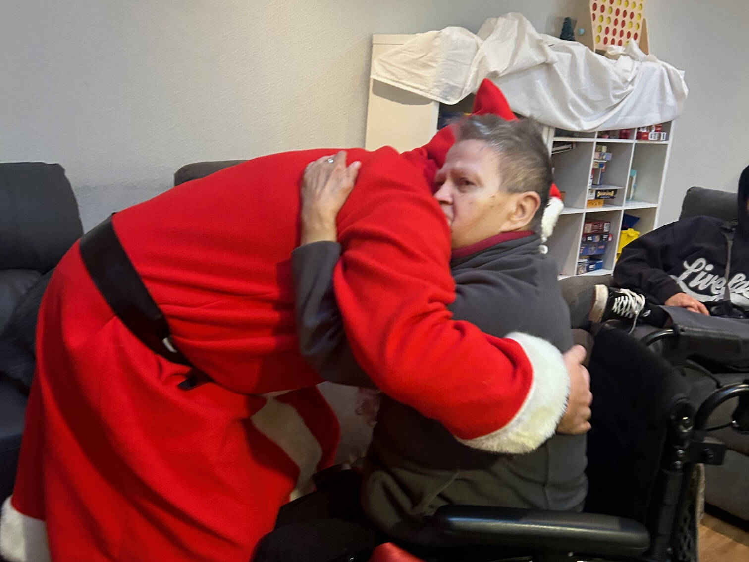 Der Nikolaus umarmt eine Person im Rollstuhl.