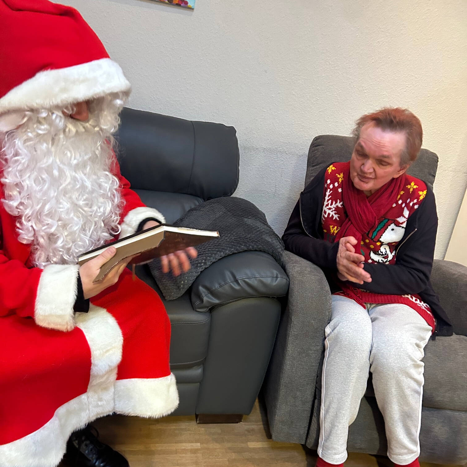 Eine Frau im Sessel hört dem Nikolaus zu.