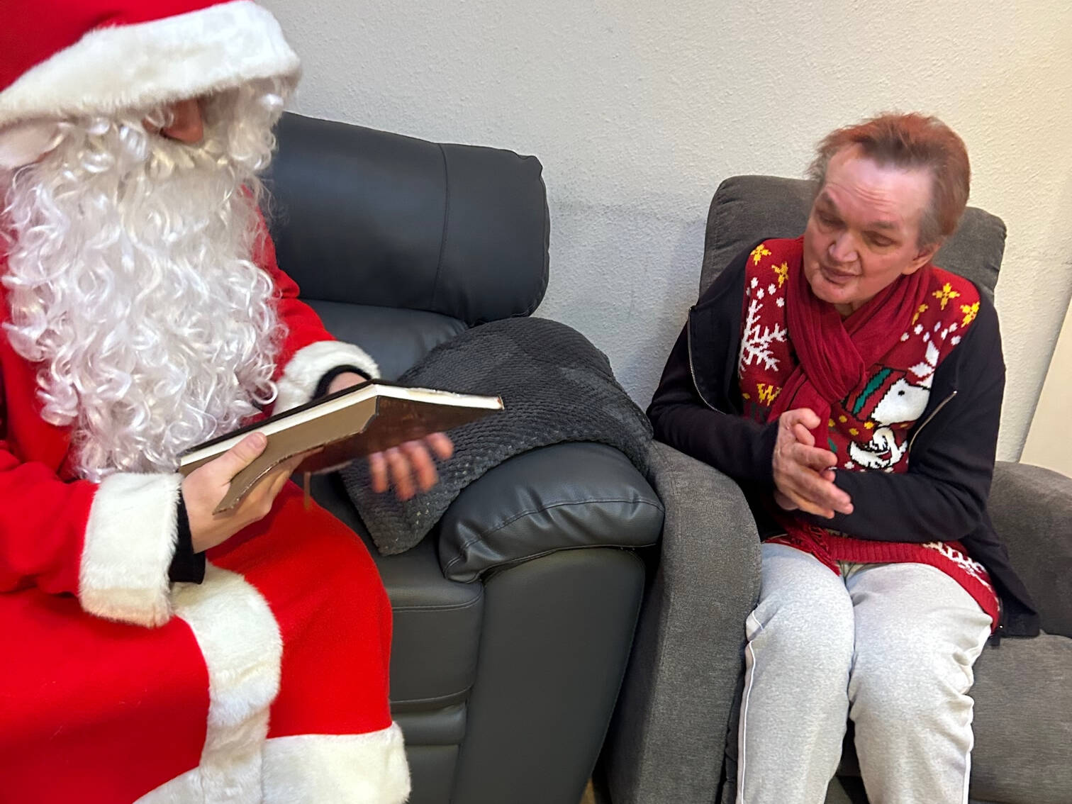 Eine Frau im Sessel hört dem Nikolaus zu.
