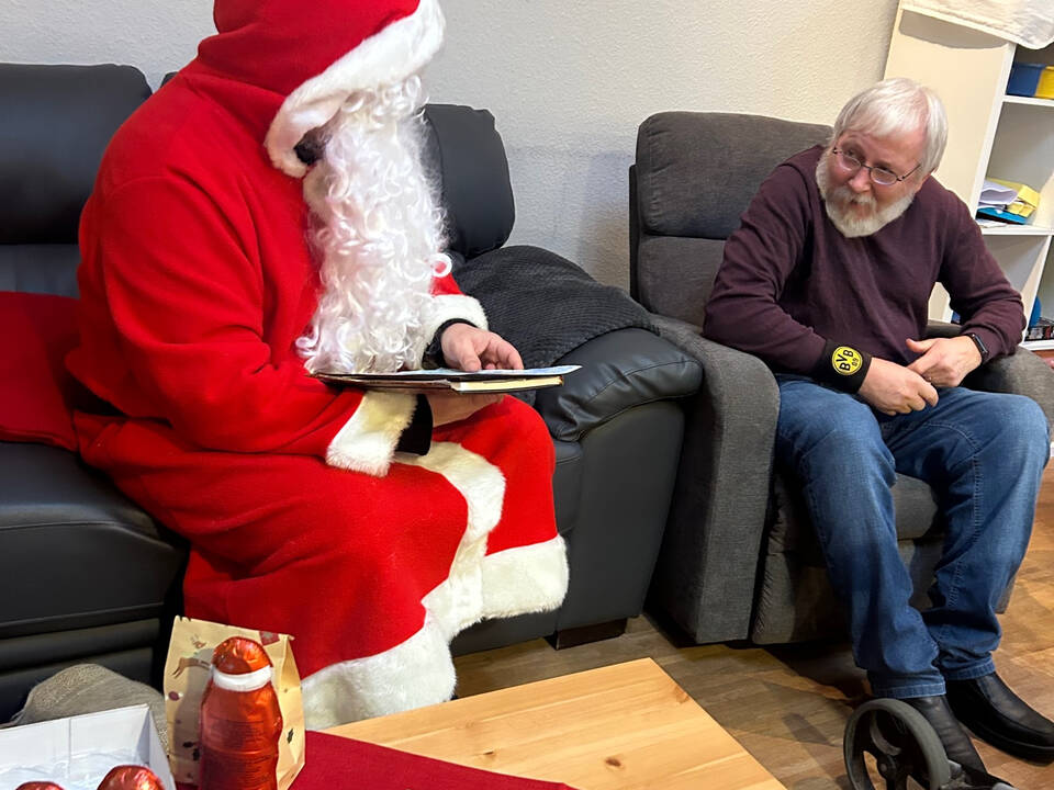 Ein Mann mit Bart hört dem Nikolaus zu.