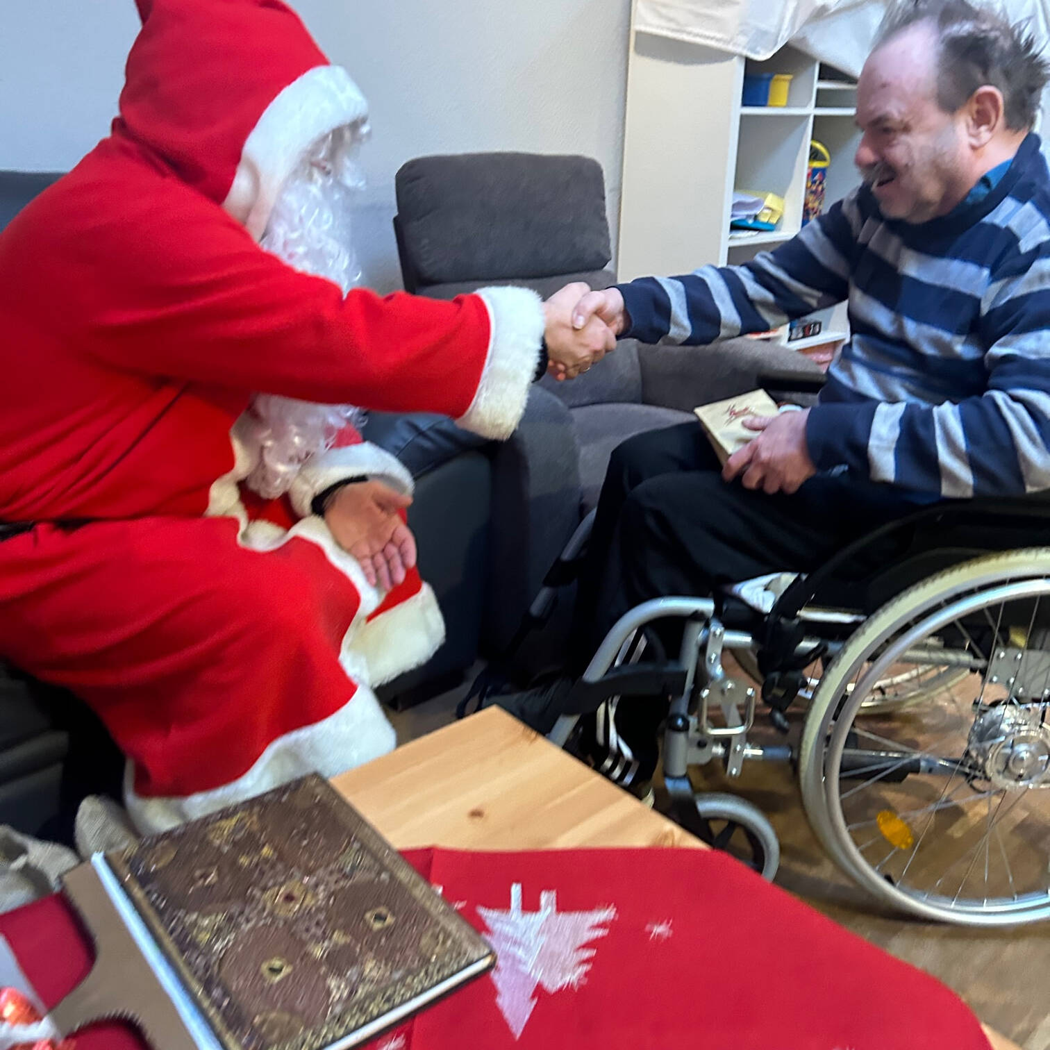 Ein Mann im Rollstuhl und der Nikolaus geben sich die Hand.