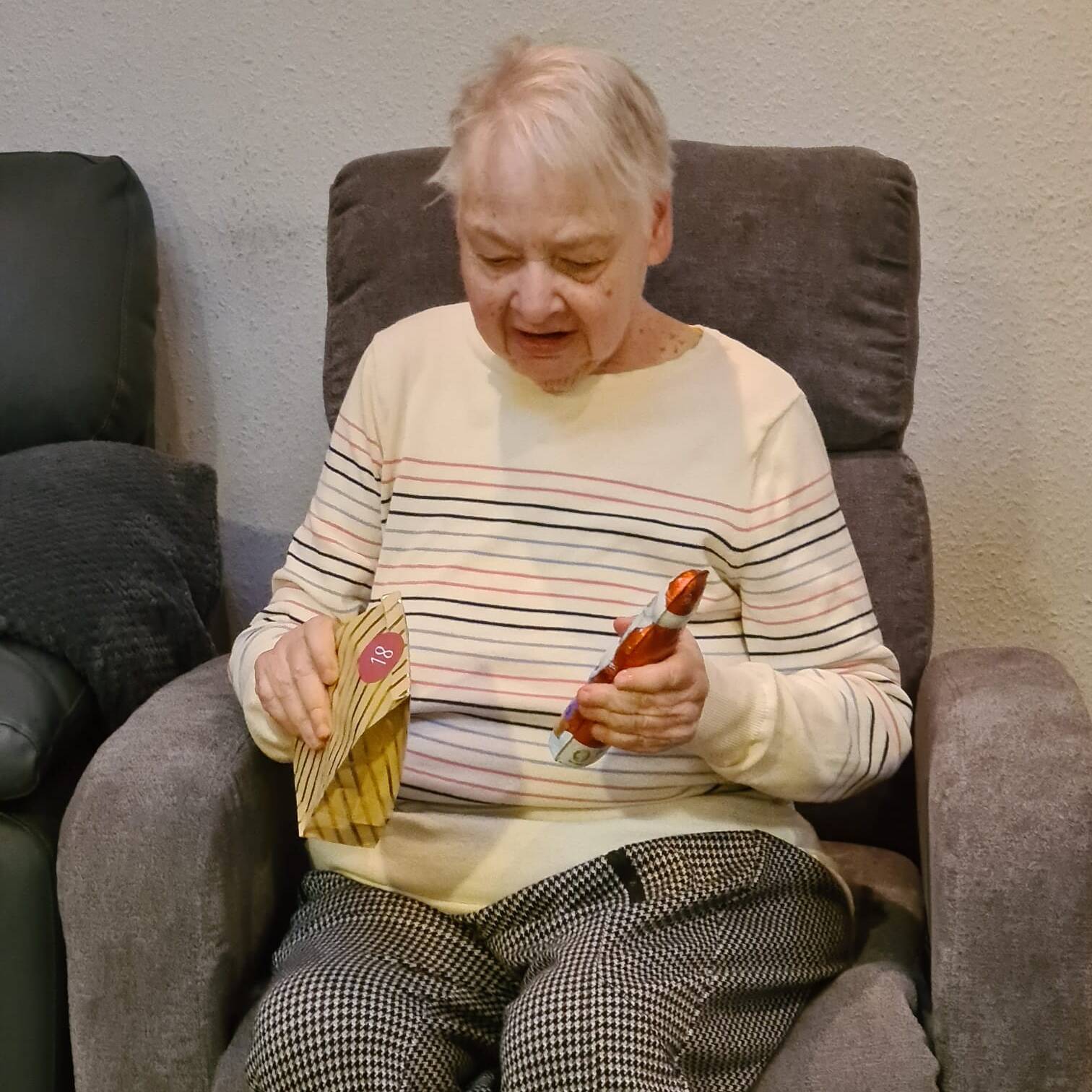 Eine Frau hält ein Geschenk und einen Schokoladennikolaus in den Händen.