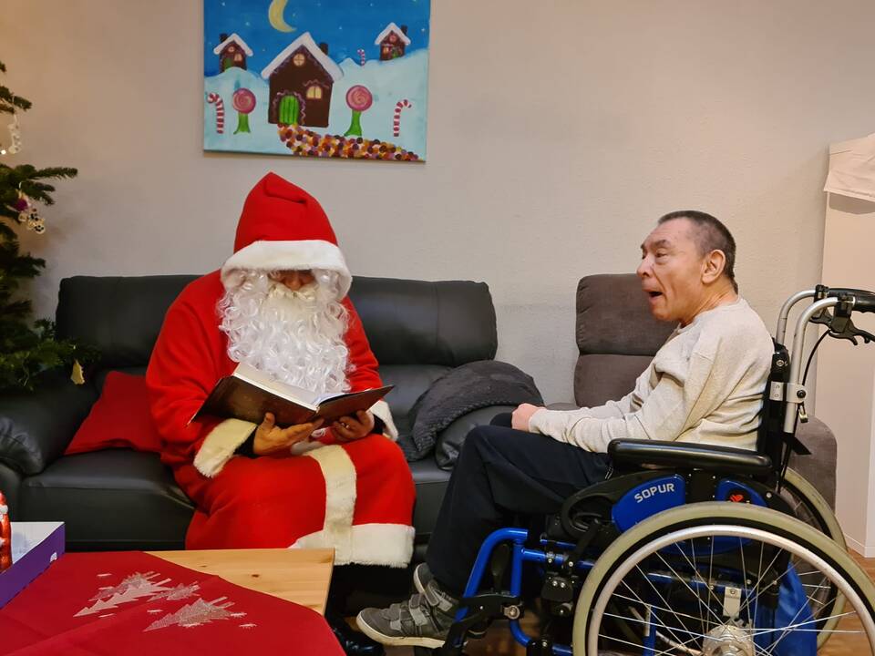 Ein Herr im Rollstuhl hört dem Nikolaus zu.