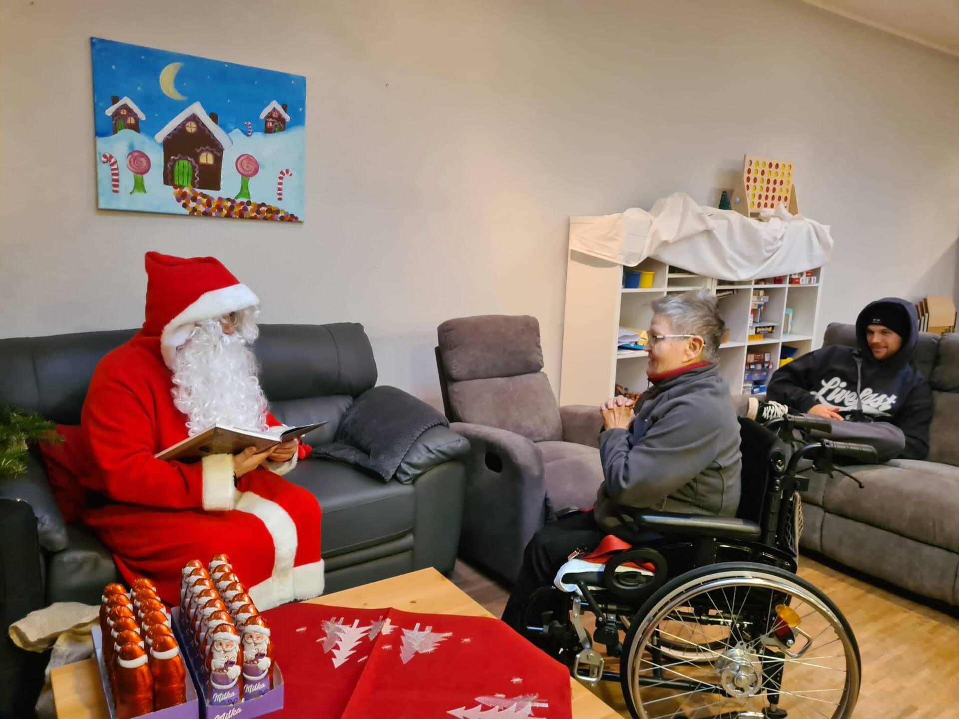 Eine Person im Rollstuhl hört dem Nikolaus zu.