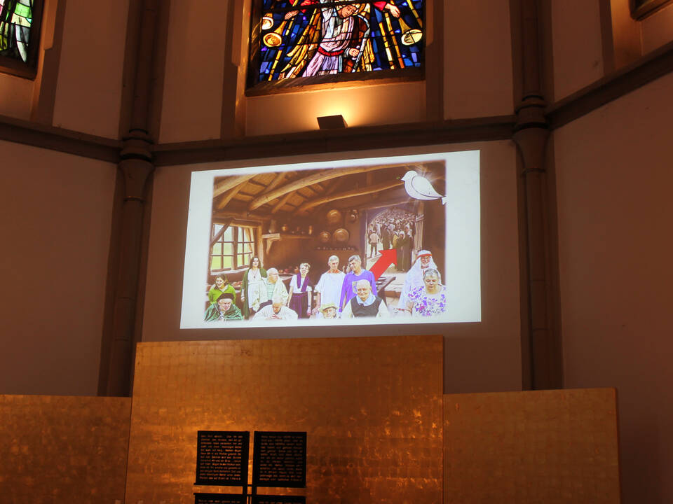 Ein Bild mit vielen Menschen wird an die Wand projeziert.